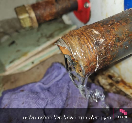 צינור חלוד עם נזילת מים על סמרטוט סגול